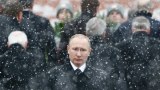 Vladimir Putin stands in the snow.