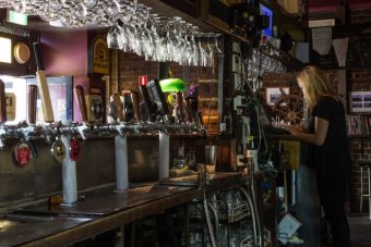 A view of the pumps and glasses behind a bar