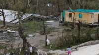 A woman stands in front of a destroyed house after Hurricane Matthew passes Jeremie, Haiti, on 5 October 2016.