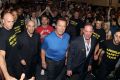 The "Arnold Safety Team" escorts the former strongman through Melbourne Exhibition Centre.