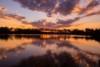 A golden sunset reflects off the waters of a full dam.  