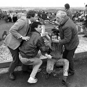 File photo dated 16/03/88 of an injured man being aided by mourners, including Sinn Fein vice president Martin McGuinness (left), at Milltown Cemetery, Belfast, after a gun and bomb attack killed three and left four seriously injured, at the funerals of three IRA members killed in Gibraltar. David Jones/PA Wire