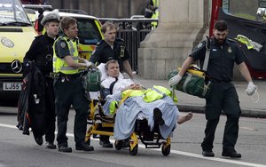 Emergency services transport an injured person to an ambulance, close to the Houses of Parliament in London, Wednesday, March 22, 2017.