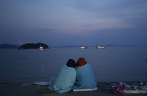 FILE- In this April 20, 2014 file photo, relatives of passengers aboard the sunken ferry Sewol sit near the sea at a port in Jindo, South Korea. (AP Photo/Lee Jin-man, File)