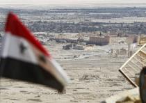  A Syrian national flag flutters as the ruins of the historic city of Palmyra are seen in the backgr