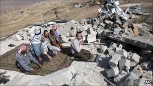 A group of Palestinian men pray on the ruins of a mosque in Khirbet Yarza