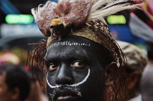 A Papuan activist donning a traditional headwear with a stuffed bird of paradise attends a protest against U.S. mining ...