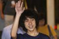Amos Yee waves as he leaves court in Singapore.