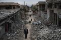 Iraqi civilians walk in a neighborhood recently liberated by Iraqi security forces on the western side of Mosul, Iraq.