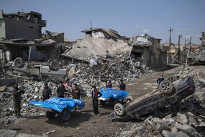 Residents carry the body of several people killed during fights between Iraq security forces and Islamic State on the western side of Mosul, Iraq, Friday, March 24, 2017.