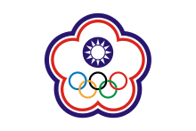 A white symbol in shape of a five petal flower ringed by a blue and a red line. In its centre stands a circular symbol depicting a white sun on a blue background. The five Olympic circles (blue, yellow, black, green and red) stand below it.