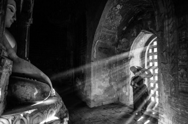 This young monk looking to Buddha in a temple in Myanmar (Burma) as the light streams through the window. Such a ...