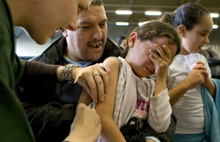 A girl gets measles vaccine administrated by a health care professional in Rotterdam, The Netherlands, as her father holds her