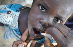 A health worker drops oral vaccination against polio into a child's mouth, in Nigeria