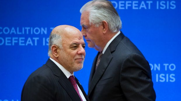 US Secretary of State Rex Tillerson, right, passes behind Iraqi Prime Minister Haider al-Abadi as he prepares to address ...