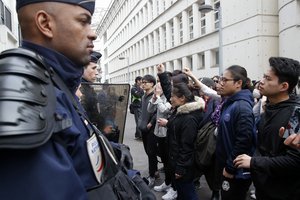 Demonstrators from the Asian community face riot police officers outside Paris' 19th district's police station, Tuesday March 28, 2017.