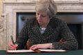 Britain's Prime Minister Theresa May signs the official letter to European Council President Donald Tusk.