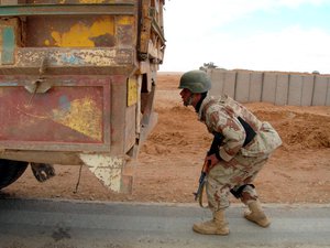 An Iraqi soldier inspects a truck at a checkpoint outside the western city of Rutbah, west of Baghdad, Iraq, Wednesday, Feb. 15, 2006.