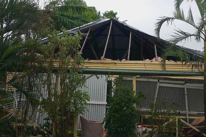 A home with a badly damaged roof and smashed windows