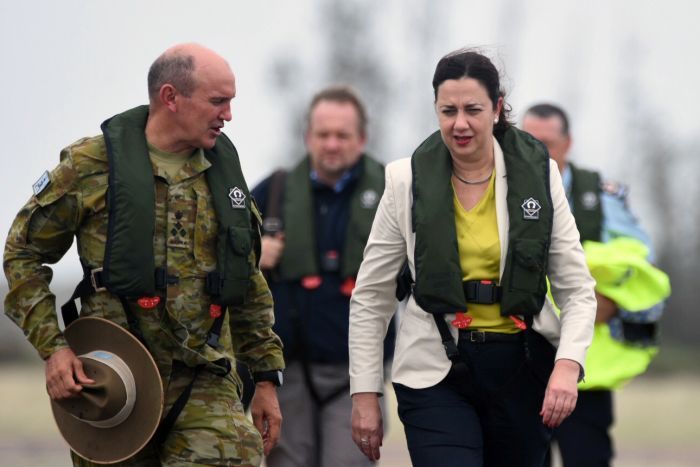 Queensland Premier Annastacia Palaszczuk walks while talking to Brigadier Christopher Field.