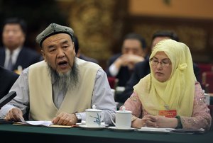 A delegate, left, from the Xinjiang Uyghur Autonomous Region speaks during the Xinjiang delegation group's meeting on the sideline of the National People's Congress at the Great Hall of the People in Beijing