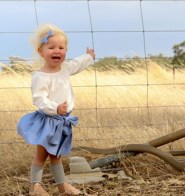 Two-year-old Molly poses for a picture as she and her mother wait for the school bus.