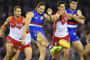 Marcus Bontempelli kicks clear under Swans pressure. 