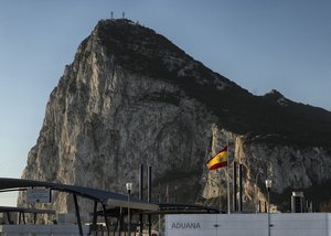 In this Wednesday, March 1, 2017 file photo, a Spanish flag flies on top of the customs house on the Spanish side of the border between Spain and the British overseas territory of Gibraltar with the Rock as a background, in La Linea de la Concepcion, Southern Spain.