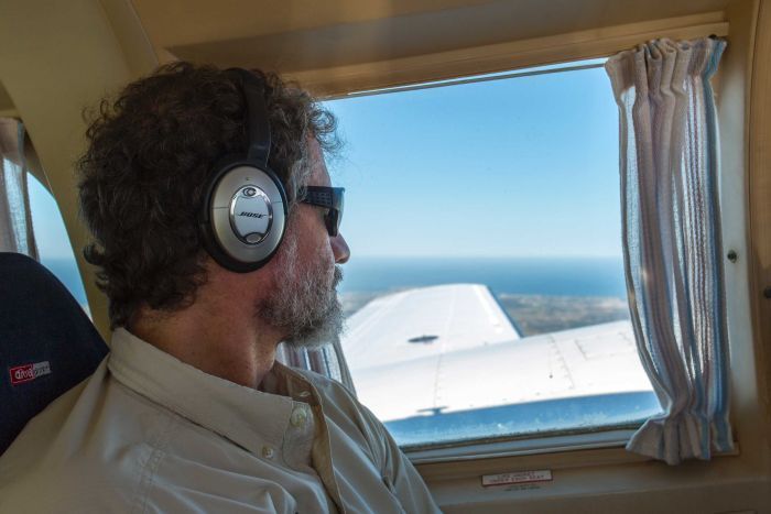 A passenger looks out over the horizon of a small charter plane