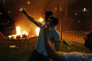 Two men pose for “selfies” during a protest against presidential re-elections at Congress, in Asuncion, Paraguay, Friday, March 31, 2017.