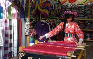 File - A Mosue girl weaver in the old town Lijiang, China.