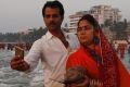 A man takes a selfie with his wife as she offers prayers to the Sun at the Arabian Sea during Chhath Puja festival in ...