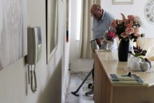 Man vacuums leaking water (ABC RN: Tim Roxburgh)