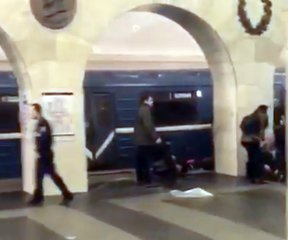 In this grab taken from AP video, Russian police officer, left, and people walk past the damaged train at the Tekhnologichesky Institut subway station in St.Petersburg, Russia, Monday, April 3, 2017.