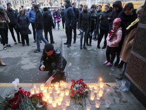 A man lights a candle at an entrance of Sennaya subway station after an explosion on the subway in St.Petersburg, Russia