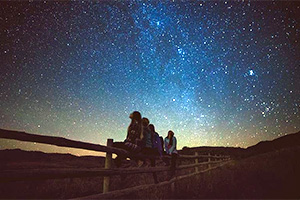 People sit on a fence looking at stars (Double J)