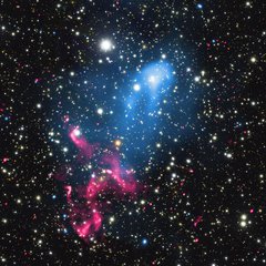 File - Astronomers have discovered what happens when the eruption from a supermassive black hole is swept up by the collision and merger of two galaxy clusters. This composite image contains X-rays from Chandra (blue), radio emission from the GMRT (red), and optical data from Subaru (red, green, and blue) of the colliding galaxy clusters called Abell 3411 and Abell 3412.