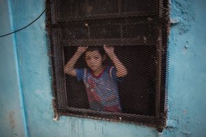 A boy peeks out of the window of his house in Nuevo Laredo, Tamaulipas state, Mexico, across the border from Laredo in ...