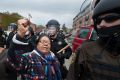 Faenette Black Bear, 63, Lakota, raises her fist in defiance as riot police push peaceful protesters away from the ...