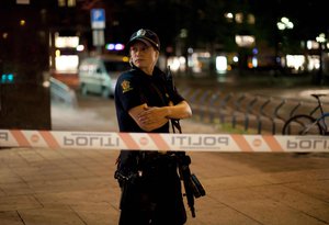 File - An armed police officer stands guard on the edge of a cordon near the site of Friday's explosion in central Oslo, Norway, in the early hours of Saturday, July 23, 2011.