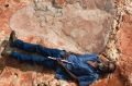 Richard Hunter lies next to a 1.7 metre dinosaur footprint belonging to a sauropod. The scale Richard is holding is 40cm ...