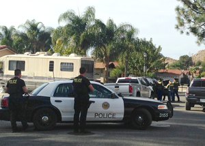 Police surround a home in Riverside, Calif., Thursday, Dec. 3, 2015, searching for evidence in connection with the shootings in San Bernardino