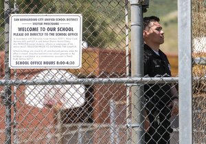 A police officer stands guard at North Park School after a shooting, Monday, April 10, 2017, in San Bernardino, Calif.. An apparent murder-suicide inside an elementary school classroom in San Bernardino left two adults dead, including a teacher, and two students wounded, police and school officials said. (AP Photo/Ringo H.W. Chiu)