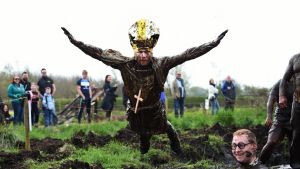 A man dressed as the Pope jumps into a pool of mud as competitors take part in the annual McVities Mud Madness 8km cross ...