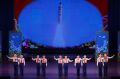 North Korean school children perform at the Mangyongdae Children's Palace while an image of a space launch vehicle is ...