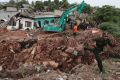 Sri Lankan army soldiers and rescue workers stand near buried houses after the collapse of a garbage dump in ...