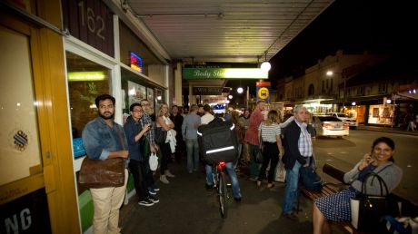 SYDNEY, AUSTRALIA - APRIL 07: A food delivery cyclist on King Street in Newtown, rides on the footpath through a busy ...