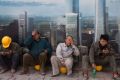 Construction workers rest near a board with an artist's impression of the Central Business District outside a ...
