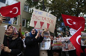 FILE-In this Wednesday, Oct. 28, 2015 file photo, protesters holding placards and waving Turkish flags demonstrate across the street from the headquarters of a media company that owns opposition television stations Bugun TV and Kanal Turk, the Bugun and Millet newspapers and other business interests, after was seized by the government, in Istanbul.