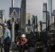 Workers stand in front of a banner featuring images of high rise towers outside a construction site in downtown Beijing.